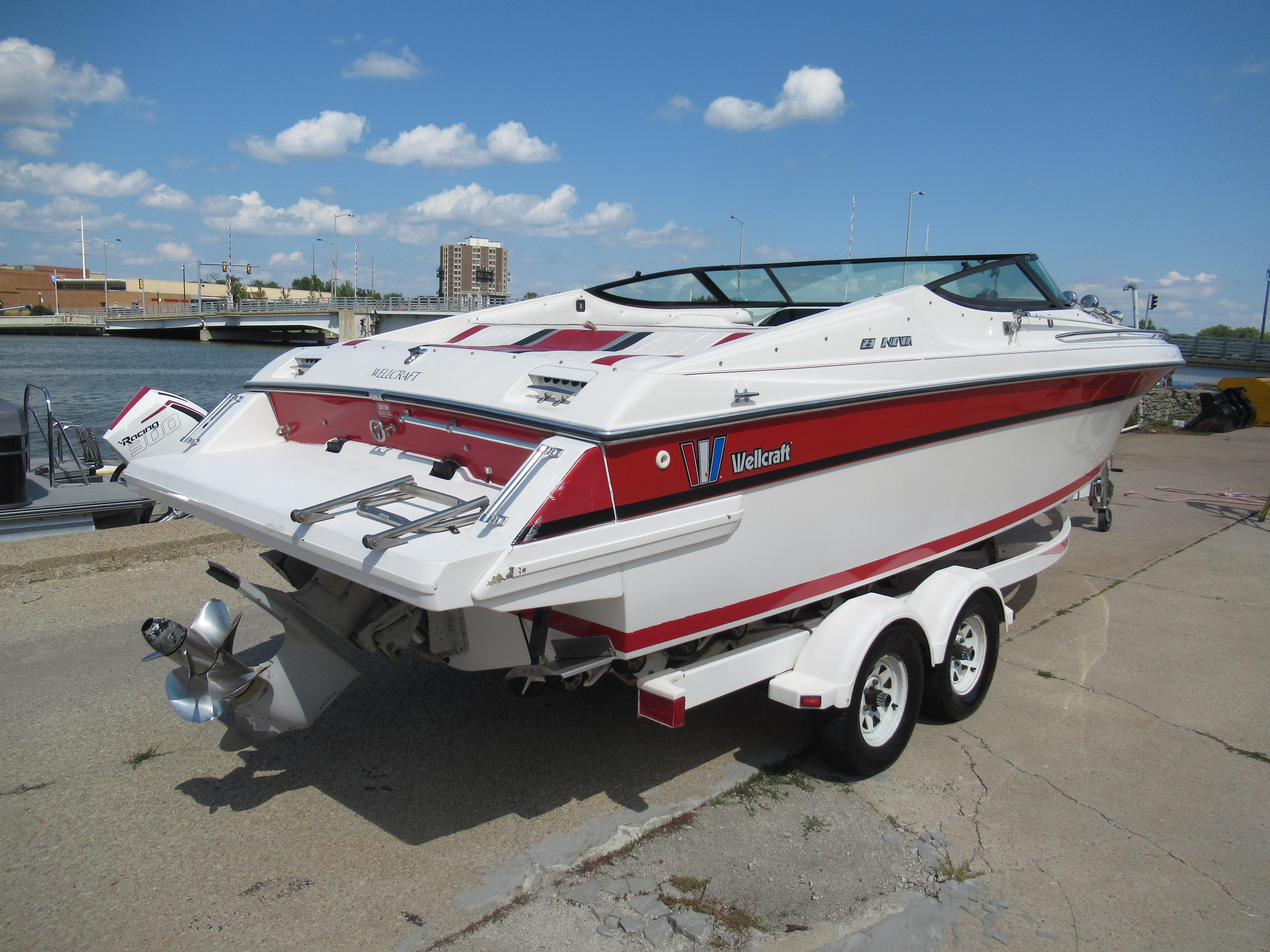 Slide: The Image of 1990 Wellcraft 23 NOVA boat on trailer by waterfront, clear sky background. - 2