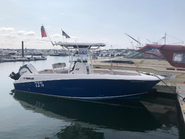 Slide: The Image of 2019 Wellcraft 242 Fisherman boat docked at marina, featuring sleek design and blue hull. - 0