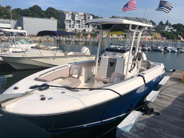 Slide: The Image of 2019 Wellcraft 242 Fisherman boat docked in marina with flags and waterfront buildings. - 3