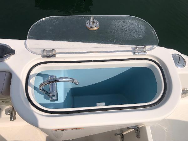 Slide: The Image of Open livewell on 2019 Wellcraft 242 Fisherman boat, featuring a transparent lid and faucet. - 37