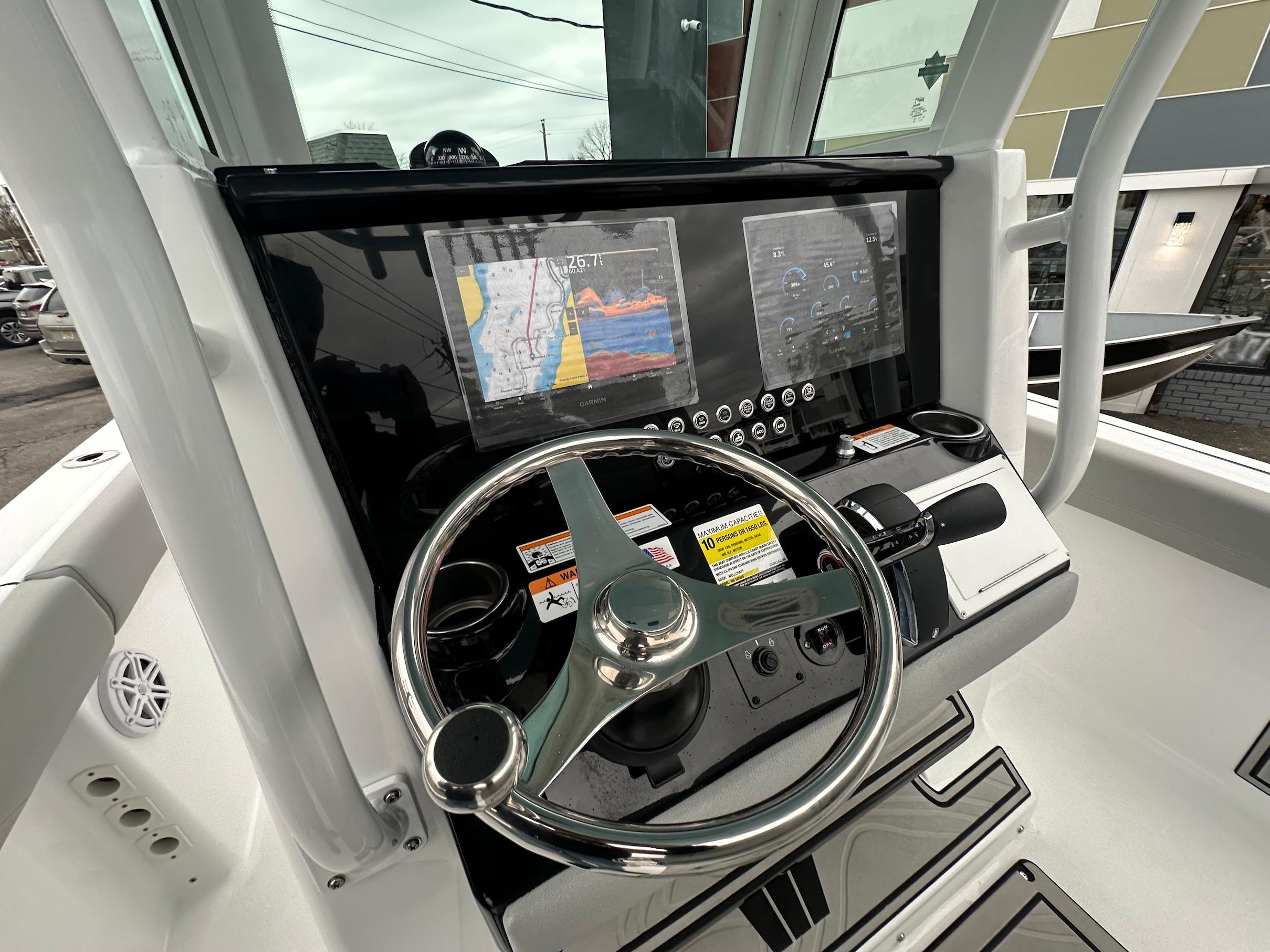 Slide: The Image of 2024 Wellcraft 243 Fisherman boat dashboard with navigation screens and steering wheel. - 15