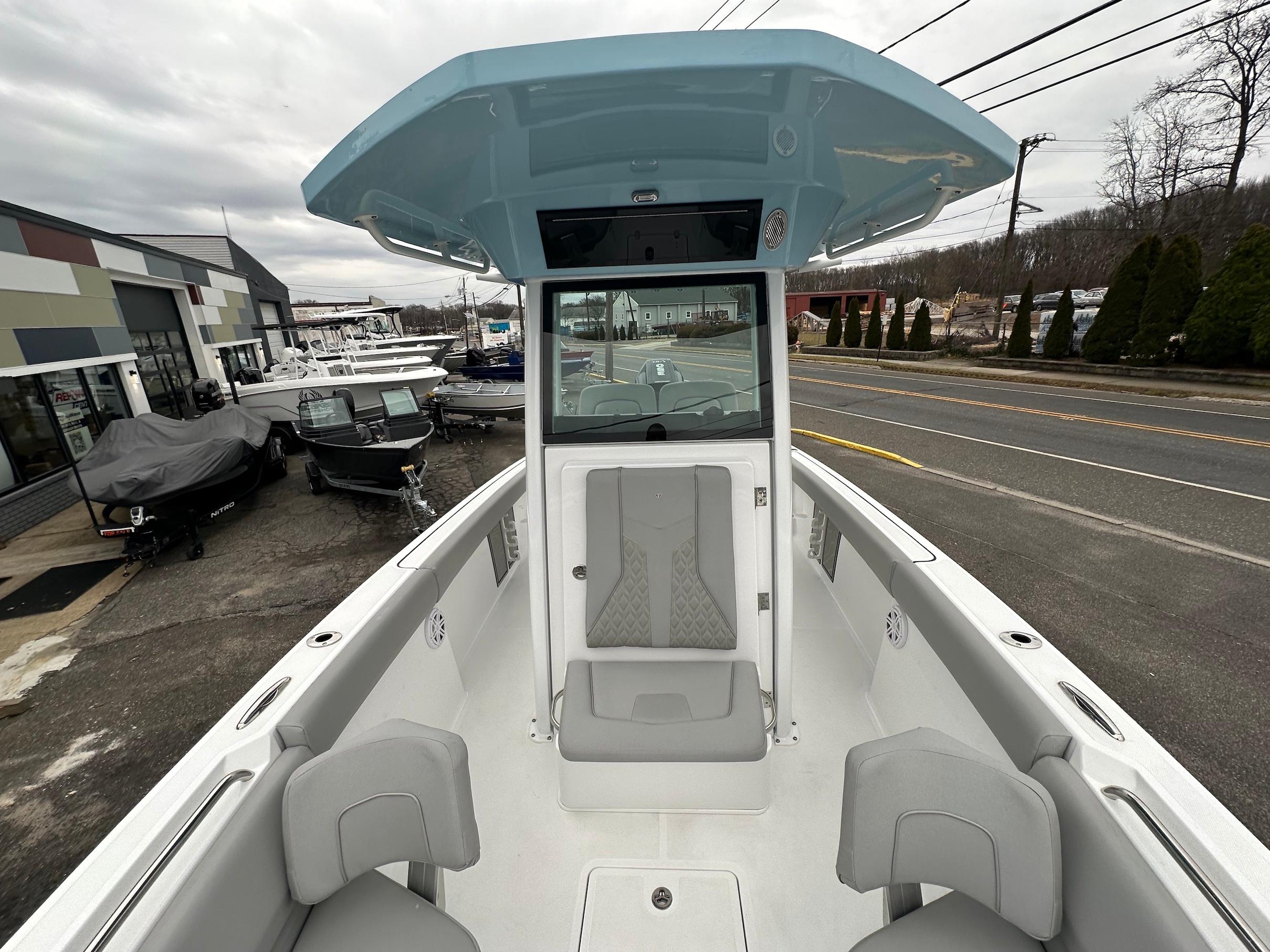 Slide: The Image of 2024 Wellcraft 243 Fisherman boat interior, docked at a dealership, showcasing seating and helm station. - 28