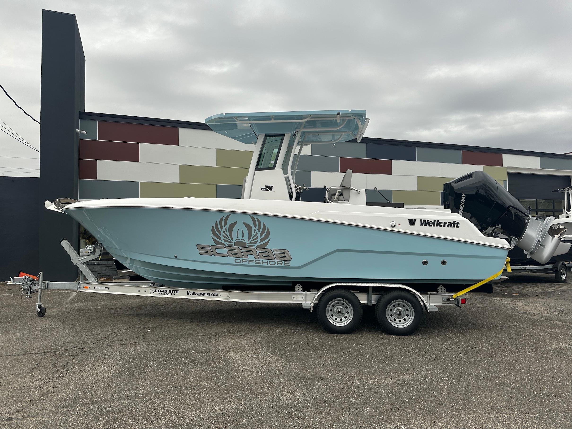 Slide: The Image of 2024 Wellcraft 243 Fisherman boat on trailer, side view, in front of a modern building. - 4
