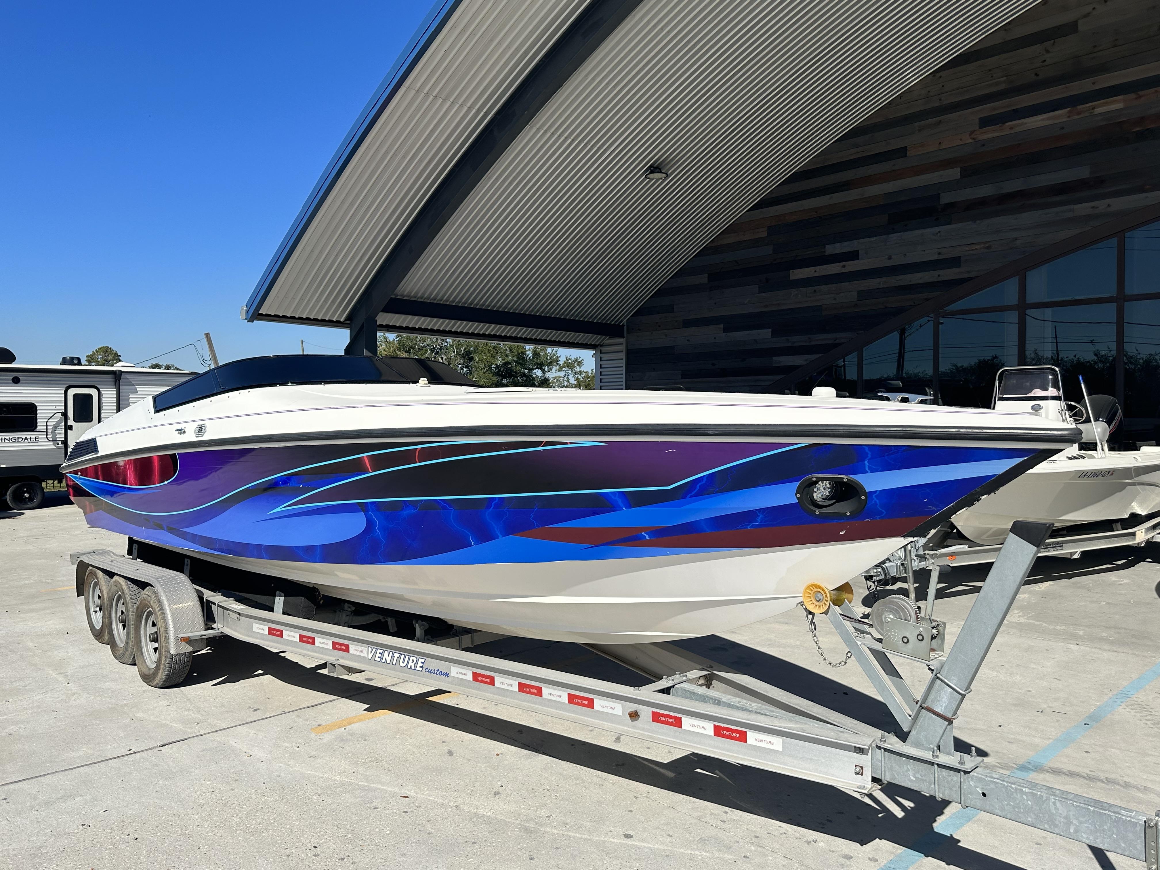 Slide: The Image of 1994 Wellcraft 2900 Sportboat on trailer, vibrant blue and purple graphics. - 0