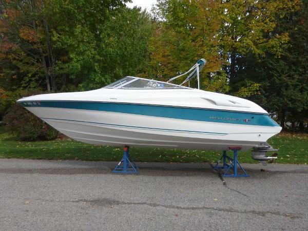 Slide: The Image of 1996 Wellcraft 2400S Eclipse boat on stands, side view, outdoors with trees in background. - 1