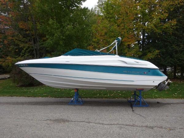 Slide: The Image of 1996 Wellcraft 2400S Eclipse boat on stands, white and teal, side view. - 2