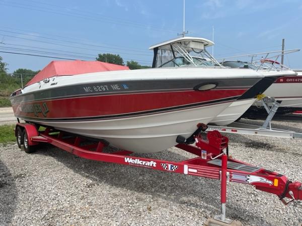 Slide: The Image of 1987 Wellcraft Nova Spyder 26 boat on a red trailer in a gravel lot. - 2