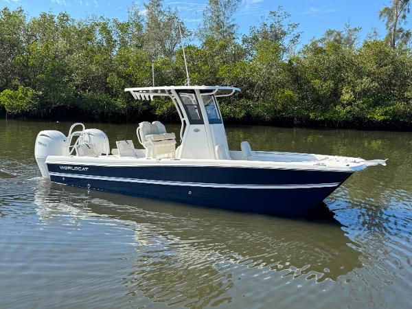 Slide: The Image of 2025 World Cat 235 CC boat on calm water, surrounded by lush greenery. - 1