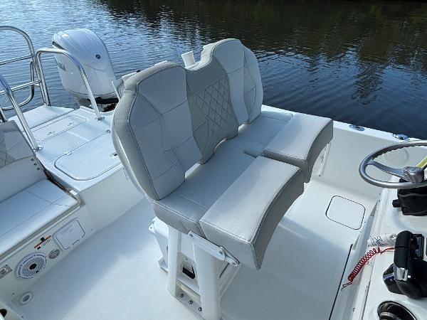 Slide: The Image of 2025 World Cat 235 CC boat with dual cushioned seats and steering wheel, near calm water. - 11