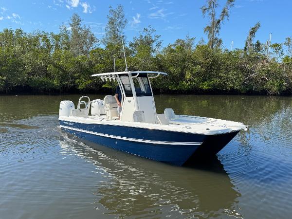 Slide: The Image of 2025 World Cat 235 CC boat cruising on a calm river with lush greenery. - 2