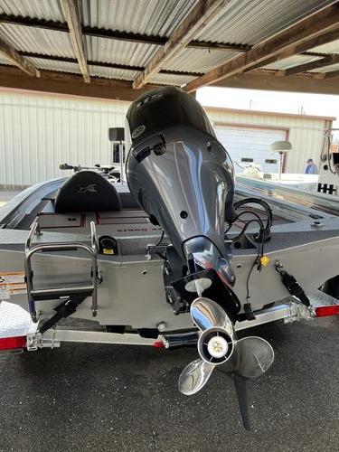 Slide: The Image of 2023 Xpress H18 boat with outboard motor, rear view under a metal roof. - 5