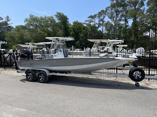 Slide: The Image of 2025 Xpress H22B boat on trailer, parked outdoors near other boats. - 0