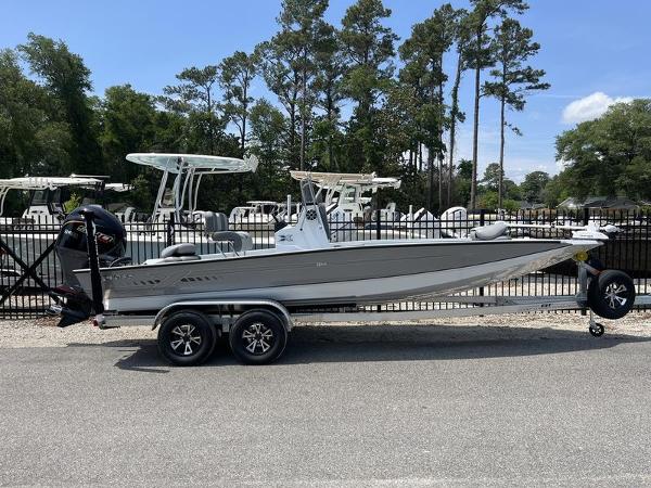 Slide: The Image of 2025 Xpress H22B boat on trailer, parked outdoors with trees in background. - 1