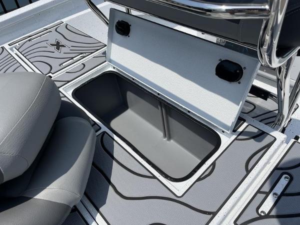 Slide: The Image of 2025 Xpress H22B boat storage compartment with open lid, gray seating, and patterned flooring. - 17
