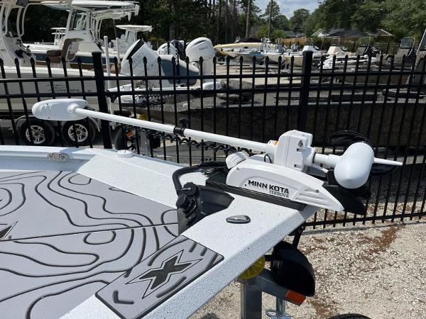 Slide: The Image of 2025 Xpress H22B boat with Minn Kota trolling motor, docked near black fence. - 19