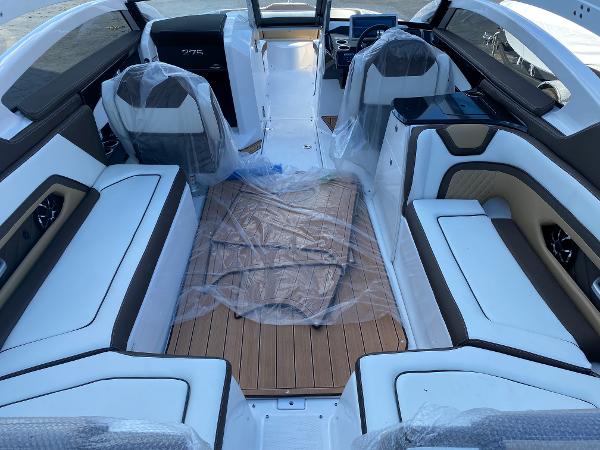 Slide: The Image of 2023 Yamaha Boats 275SE interior with white and brown seating, and wood flooring. - 4