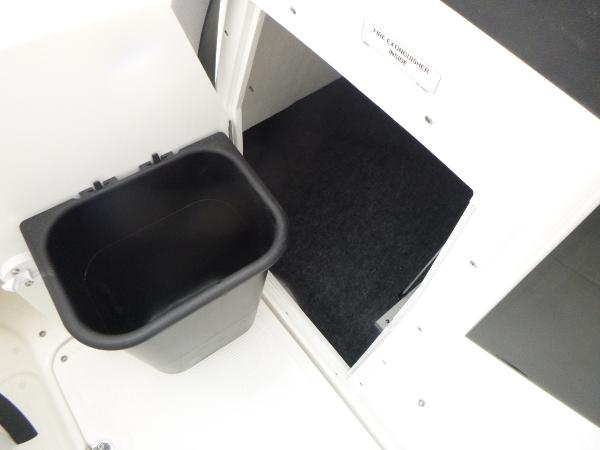 Slide: The Image of 2024 Yamaha AR195 boat storage compartment with black trash bin. - 13