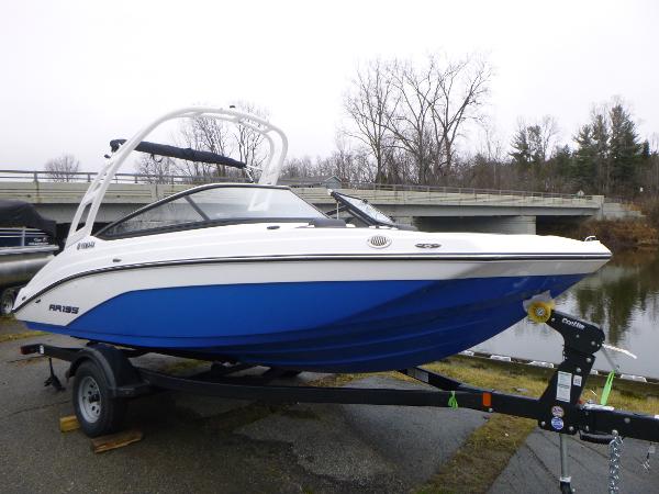 Slide: The Image of 2024 Yamaha AR195 boat on trailer near a river, overcast day. - 2