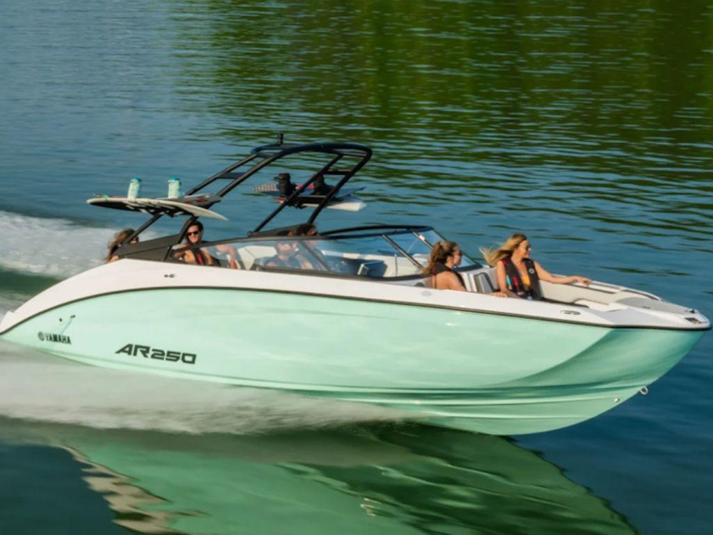 Slide: The Image of 2024 Yamaha AR250 boat cruising on a serene lake with passengers enjoying the ride. - 0