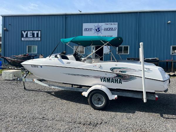 Slide: The Image of 2000 Yamaha LS 2000 boat with green canopy on trailer, parked outside Boat World store. - 1