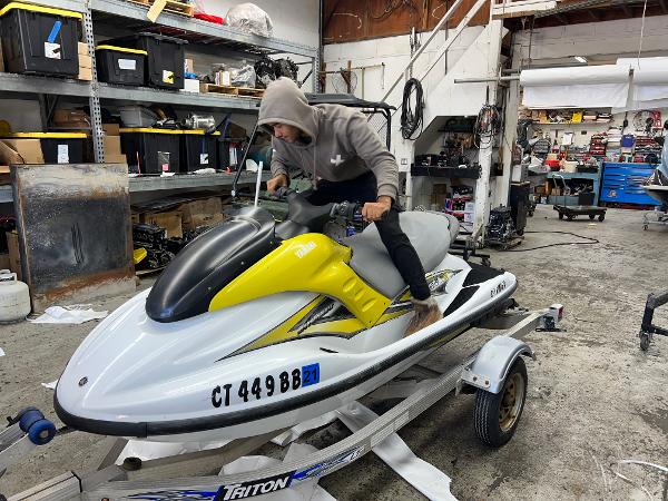 Slide: The Image of Man working on a 2005 Yamaha WaveRunner GP 800R in a cluttered workshop. - 2