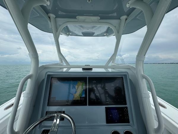 Slide: The Image of Yellowfin 32 boat dashboard with navigation screens, steering wheel, and ocean view, 2025 model. - 12