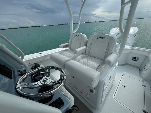Slide: The Image of 2025 Yellowfin 32 boat interior with white seating and steering wheel, overlooking calm waters. - 14