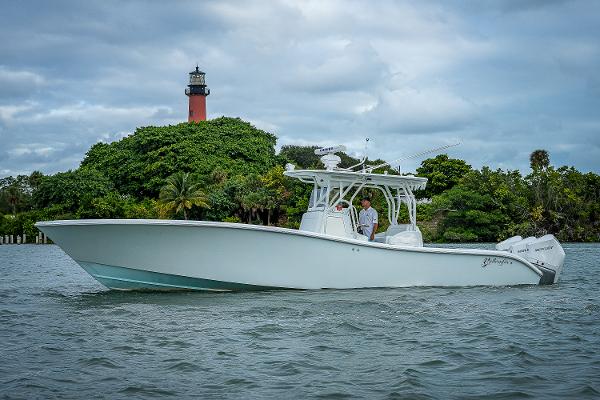 Slide: The Image of 2009 Yellowfin 36 boat cruising near a lighthouse with lush greenery. - 0