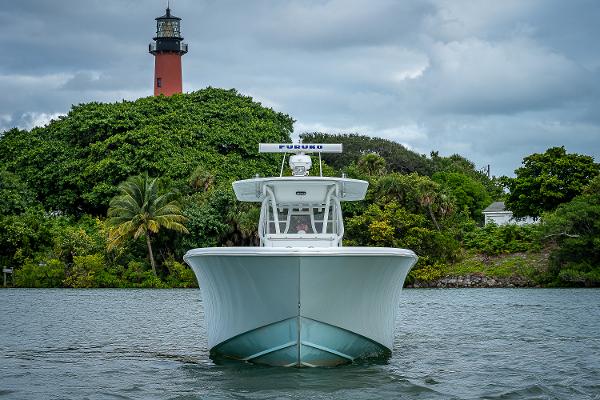 Slide: The Image of 2009 Yellowfin 36 boat on water with lighthouse and greenery in background. - 2