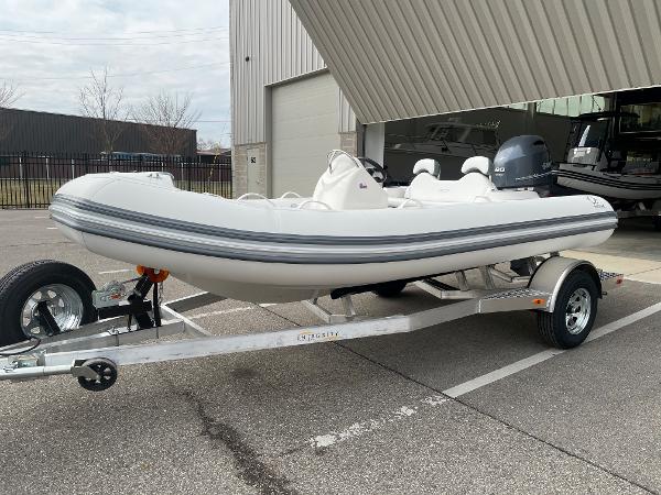 Slide: The Image of 2023 Zodiac Yachtline 490 Deluxe NEO 90hp on trailer, parked outside a building. - 4